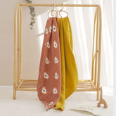 Happy Koala swaddle and mustard blanket hanging together from wooden peg